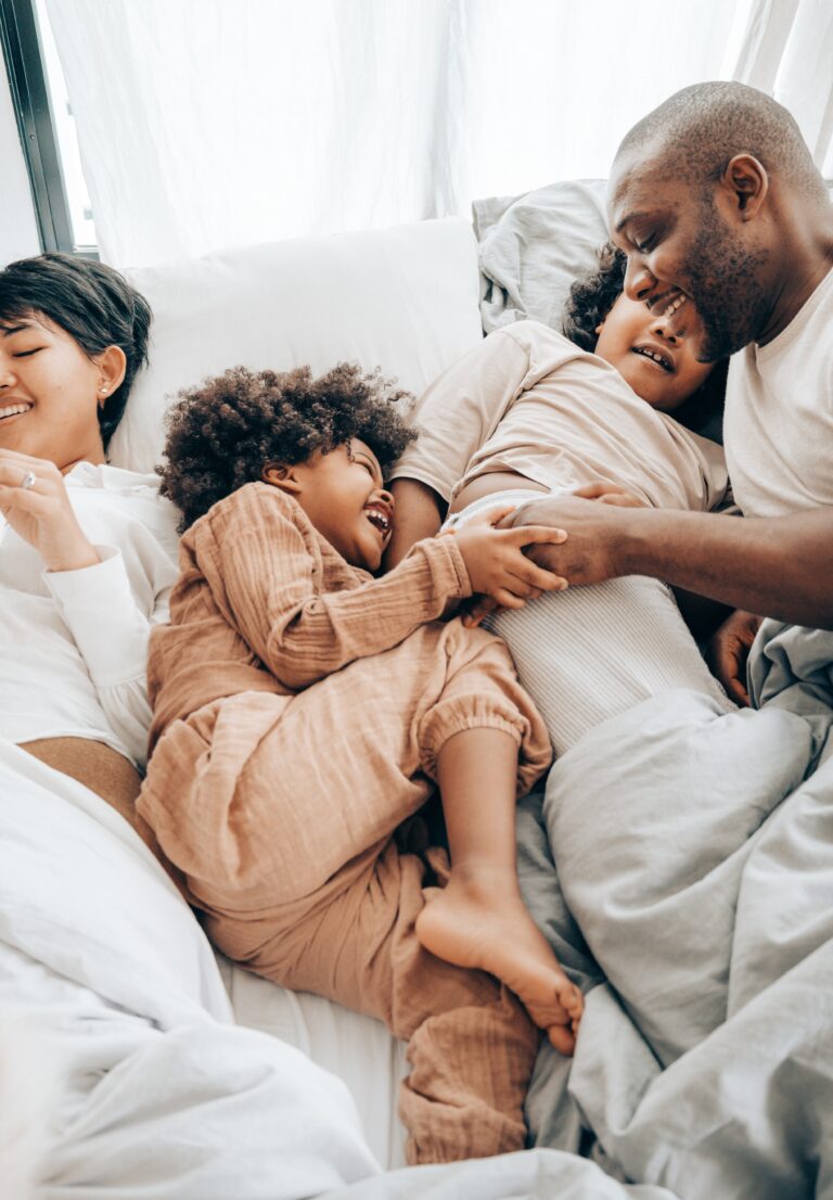 family smiling and cuddling in bed after lytle dental cleanings