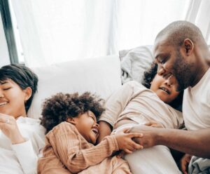 family smiling and cuddling in bed after lytle dental cleanings